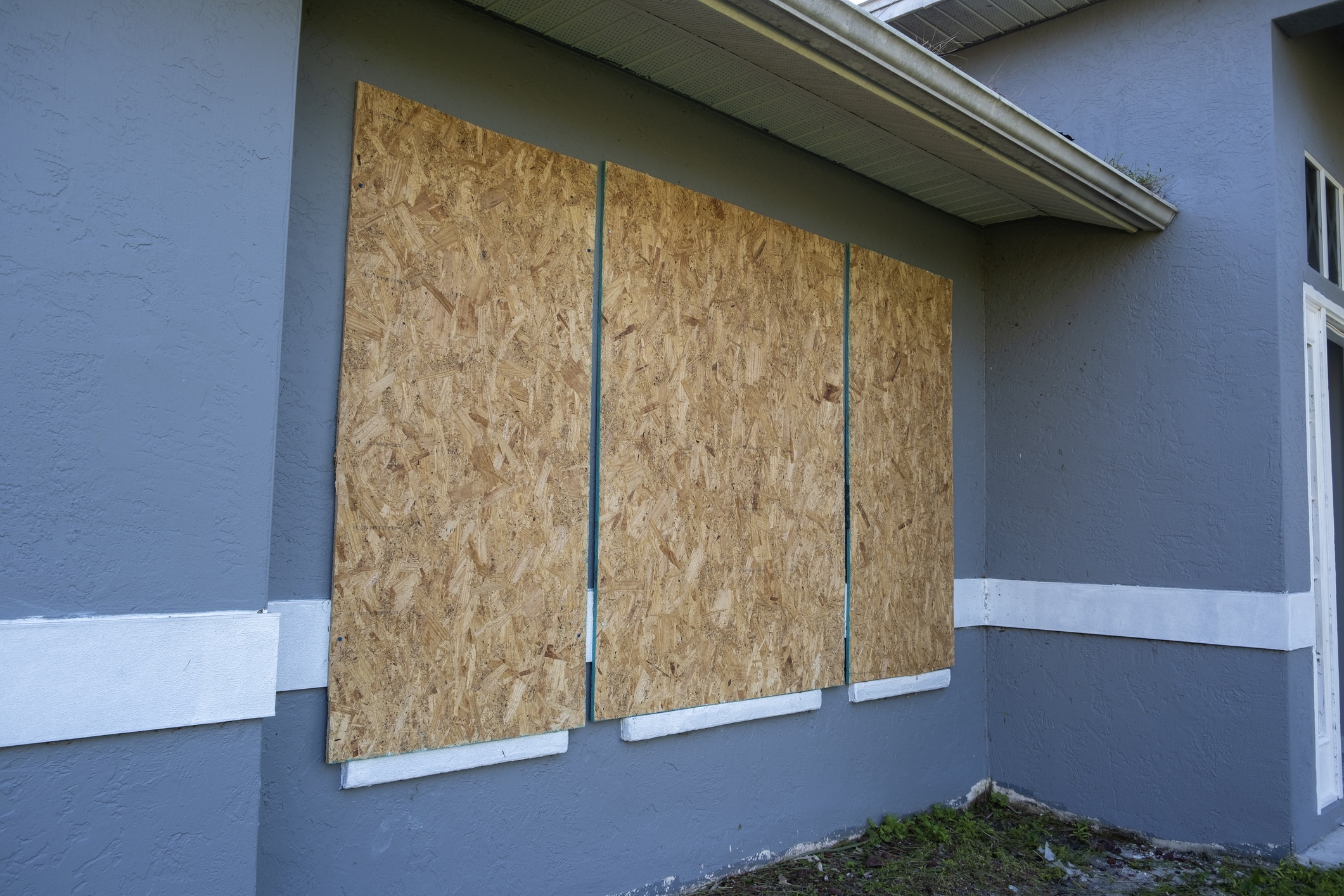 Hurricane shutters made from plywood mounted for protection of house windows. Protective measures before natural disaster in Florida.
